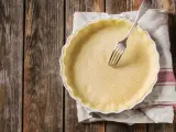 Pâte brisée sans beurre dans un plat à tarte, prête à être garnie. Une fourchette est plantée dans la pâte.