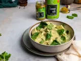 Aksamitny kurczak w zielonym curry, udekorowany świeżym szpinakiem i kolendrą. Obok puszka mleka kokosowego i słoiczek pasty curry.