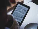 Osoba czyta książkę w formacie kindle. Na ekranie widoczny jest tekst powieści.