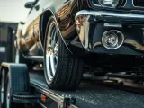 Czarne auto na lawecie, widoczna przednia część i koło.
