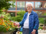 An elderly woman smiles, tending to flowers outside the St. Rose of Viterbo Convent.
