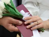 Para weselna trzyma bukiet białych tulipanów i akt małżeństwa. Zastanawiasz się, ile się daje na wesele?