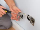 Elektryk montuje gniazdko, co może być związane z problemem braku uziemienia w domu.