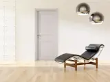 Divano in pelle nera e metallo, con un'elegante porta tortora e un muro con texture geometrica. Un perfetto abbinamento tortora e verde per un ambiente moderno.