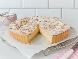 Eine köstliche Torta della Nonna, bestäubt mit Puderzucker und Pinienkernen, wartet darauf, angeschnitten zu werden.