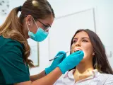 Dentystka w masce i rękawiczkach bada zęby pacjentki. To nie jest wyrywanie 8, ale rutynowa kontrola.