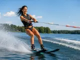 Frau beim Wasserskifahren auf dem Langenfelder See, die mit einem breiten Lächeln über das Wasser gleitet.