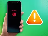 Hand hält Smartphone mit "SPAM"-Anzeige und rotem Hörer-Symbol. Daneben ein Warnzeichen. Call screening schützt vor unerwünschten Anrufen.