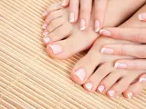 Zadbany pedicure french na stopach i dłoniach, prezentujący klasyczną elegancję na bambusowym tle.