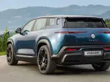 Tylna część niebieskiego elektrycznego SUV-a Fisker Ocean na tle gór i zieleni.