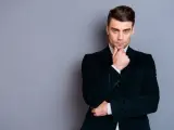 Elegancki mężczyzna w ciemnej, **marynarce aksamitnej męskiej**, z dłonią na podbródku, spogląda wprost.