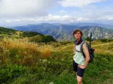 Donna con zaino e bastoncini da trekking ammira il panorama montuoso, un'emozione delle camminate FVG.