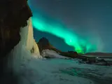 Lodowy wodospad i zorza polarna na nocnym niebie. Islandia w styczniu, magiczny widok.