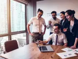 Zespół świętuje sukces. Mężczyzna, który jest business development managerem, wskazuje na ekran laptopa.