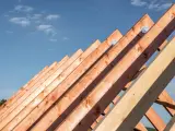 Drewniane krokwie dachowe pod błękitnym niebem. Sprawdź aktualną krokwie dachowe cenę i zaplanuj budowę.