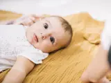 Niemowlę leży na musztardowym kocyku. Kiedy się niepokoić, gdy dziecko nie chodzi? Zwykle nie ma powodu do obaw, jeśli maluch rozwija się prawidłowo.