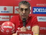 Jota González, trener reprezentacji Polski w piłce ręcznej, przemawia do mikrofonu. Obok niego czerwona piłka.