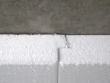 Detailaufnahme: Styrodur kleben an einer Betonwand. Die weißen Styroporplatten sind präzise zugeschnitten und stoßen nahtlos aneinander.