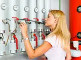 Frau prüft die Einstellungen an einer modernen Gasheizung, bereit für 2026.