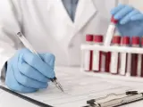 Laborant w rękawiczkach zapisuje dane pacjenta, obok stoją probówki z krwią do analizy CRP.