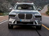 Szary BMW X7M pędzi krętą drogą przez pustynny krajobraz.