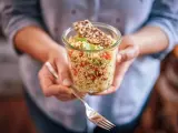 Un bocal rempli de quinoa coloré, parfait pour un régime sain. Une fourchette est prête à déguster ce plat savoureux.
