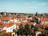 Widok na dachy Pragi, idealne miejsce na tani city break. W oddali wieże i kopuły.