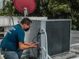 Technik sprawdza czujnik ciśnienia klimatyzacji, podłączając manometr do jednostki zewnętrznej.