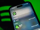 Telefon z aplikacją Spotify, sugerującą muzykę w jakości **spotify lossless**. Zielone logo Spotify w tle.