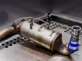 Metalowy element układu wydechowego, prawdopodobnie zawór EGR, leży na metalowej powierzchni.