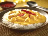 Straccetti di pollo al curry su un letto di riso bianco, guarniti con peperoncino rosso fresco. Un piatto invitante e saporito.
