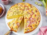 Saftiger Rhabarberkuchen, ein Klassiker unter den Rezepten mit Rhabarber. Ein Stück wird gerade herausgehoben.