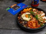 Pyszny Bibimbap przepis: ryż, kurczak, jajko sadzone, grzyby, marchewka i kimchi. Obok opakowanie pasty kimchi.