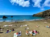 Słoneczne madera plaże z turystami kąpiącymi się w turkusowym oceanie i opalającymi się na piasku.