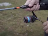 Daiwa Fuego Camo Spin Test: Eine Hand hält eine Angelrute mit Camo-Griff und einer Rolle mit blauer Schnur.