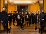Grupa profesjonalistów w czarnych strojach pozuje w eleganckim wnętrzu.