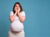 Donna incinta con le mani sul viso esprime paura in gravidanza, preoccupata per il futuro.