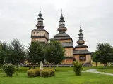 Drewniana cerkiew z trzema kopułami, otoczona zielenią. Wspaniałe krempna atrakcje dla miłośników historii i architektury.
