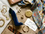 Elegancki zestaw: perfumy damskie bucik, złota biżuteria, jedwabna apaszka i brązowy portfel.