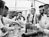 Panowie w eleganckich koszulach i szelkach świętują, paląc cygara i pijąc. Świetne kawalerski pomysły na wspólne chwile.