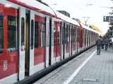Czerwony pociąg na stacji. Ludzie czekają na peronie, zastanawiając się, jak zwrocic bilet.