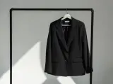 Schwarzer Blazer hängt auf einem Kleiderbügel. Zeit, den Blazer zu waschen und frisch zu machen.