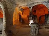 Wnętrze skalnego kościoła w Kapadocji. Pomarańczowe światło oświetla łuki i kolumny wykute w skale, tworząc mistyczną atmosferę tego starożytnego miasta.