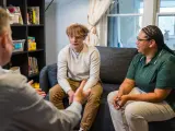 Trzy osoby siedzą na kanapie podczas sesji terapeutycznej.