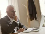 Biznesmen w garniturze zamyślony nad laptopem, przygotowuje się do wszczęcia śledztwa.