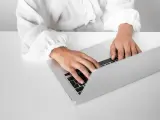 Osoba w białej koszuli pisze na laptopie, przygotowując zaświadczenie o niezaleganiu ZUS.