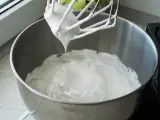 Ubita śmietana z mascarpone, idealne proporcje dla puszystego kremu. Mikser z białą masą w metalowej misie.