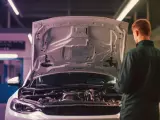 Meccanico esamina il motore turbo aspirato di un'auto con il cofano aperto in officina.