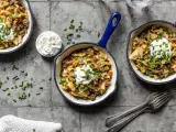 Herzhafte spitzkohl hack pfanne mit einem Klecks Sauerrahm und Schnittlauch garniert, serviert in kleinen Gusseisenpfannen.