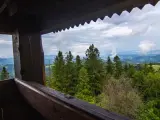 Widok z drewnianej wieży widokowej na górzysty krajobraz. W oddali widać mgły unoszące się nad dolinami, a na pierwszym planie las. To idealne miejsce dla koziarza szukającego spokoju.